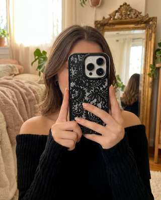 Black Frame lace phone case held up in a cosy bedroom